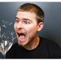 "Surprised man reacting to a shattering glass, with fragments flying."