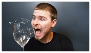 "Surprised man reacting to a shattering glass, with fragments flying."