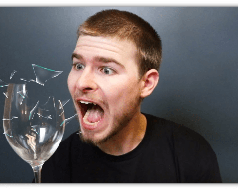 "Surprised man reacting to a shattering glass, with fragments flying."
