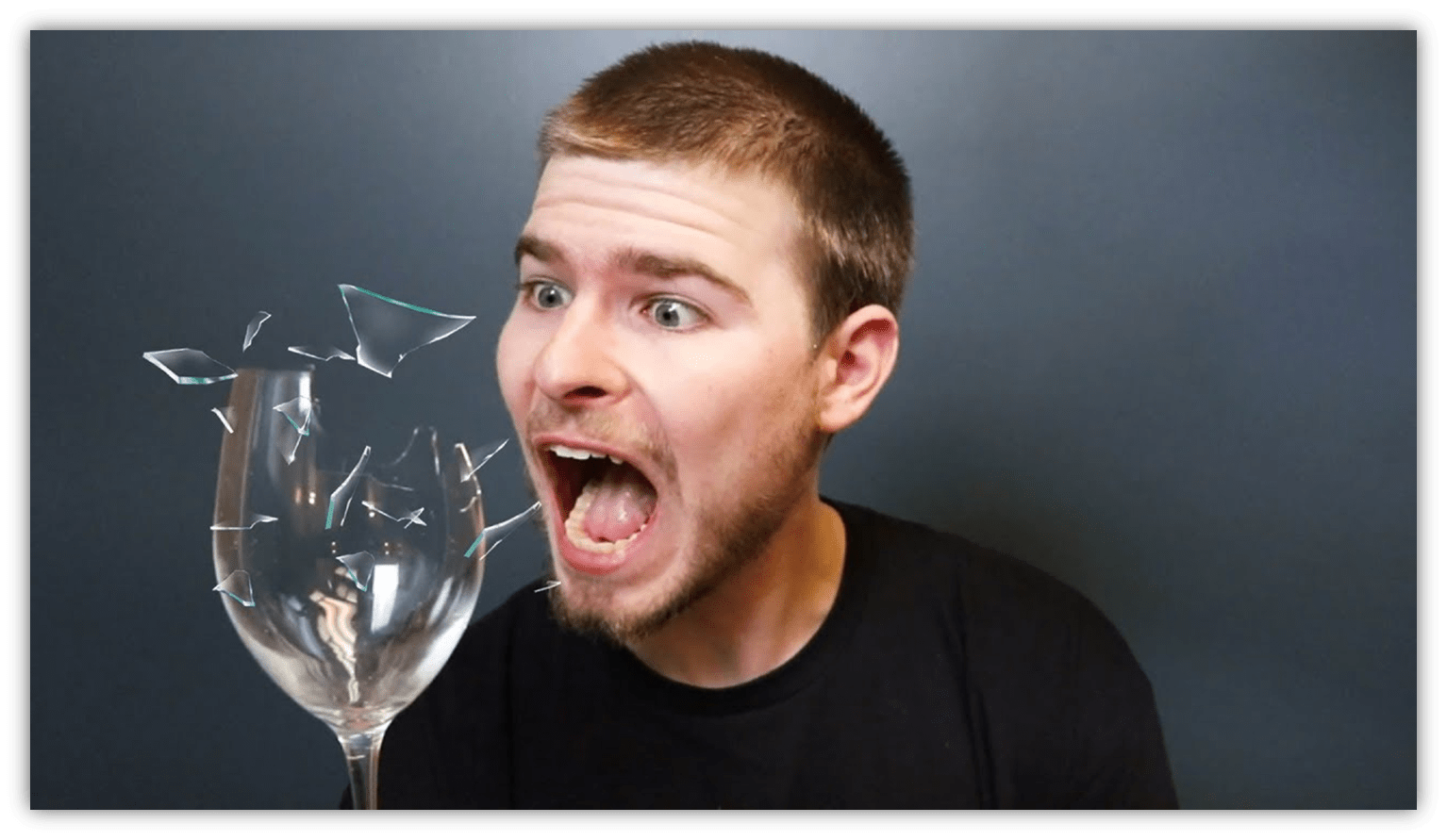 "Surprised man reacting to a shattering glass, with fragments flying."