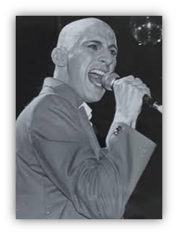 Black and white image of a bald male singer passionately performing on stage with a microphone.