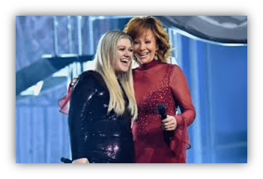 "Kelly Clarkson and Reba McEntire perform together on stage, smiling and engaging with the audience."