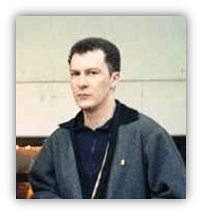 Young man in a gray jacket standing indoors.