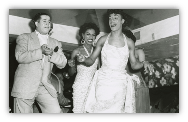 "Vintage black and white photo of performers in drag, celebrating on stage with lively expressions."