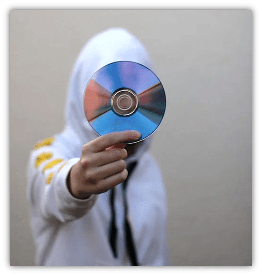 Person in a hoodie holding a CD against a neutral background.