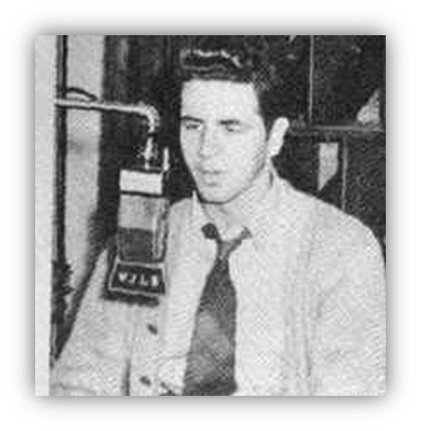 "Black and white photo of a young man sitting near a microphone."