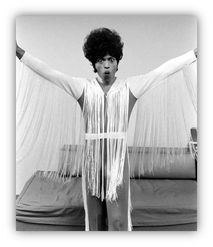 "Person in a fringed outfit striking a dramatic pose."