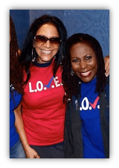 Two women smiling, wearing colorful "L.O.V.E." t-shirts, promoting positivity and unity.