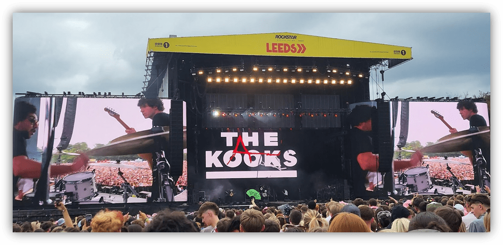 The Kooks performing live at Leeds Festival, with large screens displaying the band and a crowd in attendance.