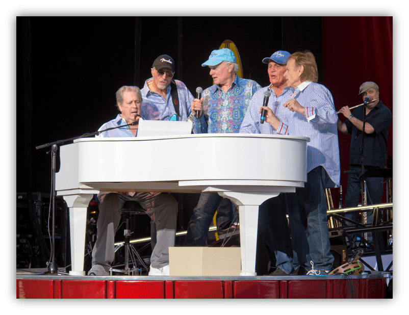 "Musicians performing at a live concert around a white piano."