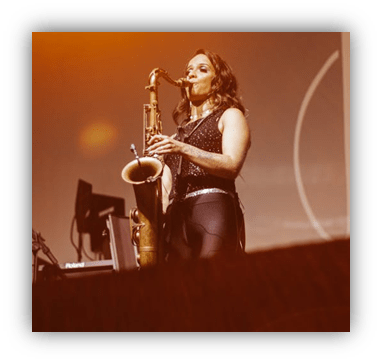 "Female saxophonist performing on stage with vibrant lighting."