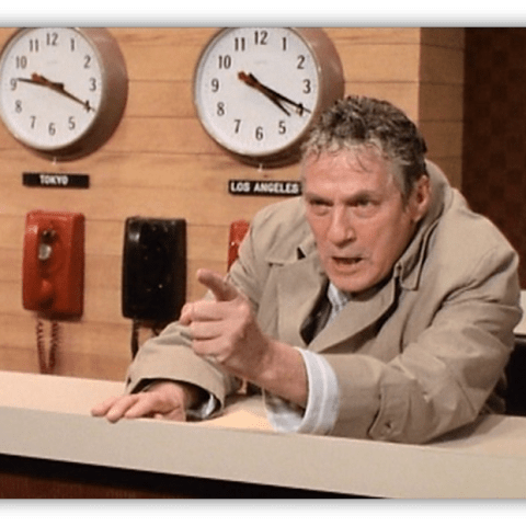 "Angry news anchor gesturing in a studio with clocks for Tokyo and Los Angeles in the background."