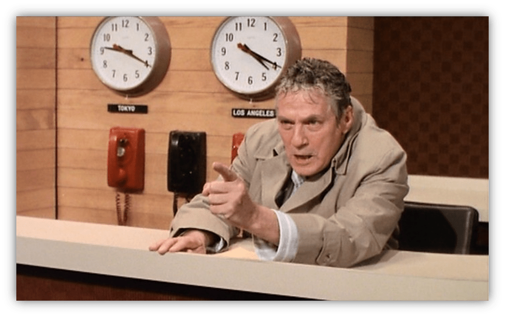 "Angry news anchor gesturing in a studio with clocks for Tokyo and Los Angeles in the background."