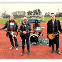 "Band performing on a sports field, featuring guitarists and a drummer."