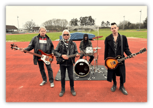 "Band performing on a sports field, featuring guitarists and a drummer."