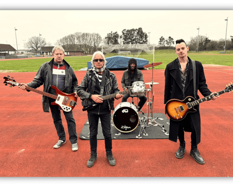 "Band performing on a sports field, featuring guitarists and a drummer."