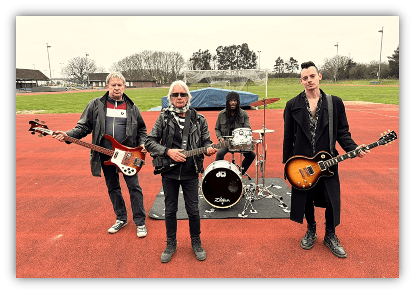 "Band performing on a sports field, featuring guitarists and a drummer."