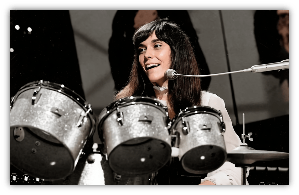 "Smiling female drummer performing with a silver drum set on stage."
