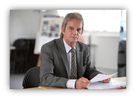 Businessman in a suit reviewing documents at a desk.