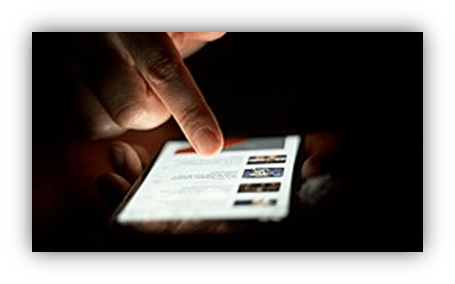"Close-up of a hand using a smartphone in low light."