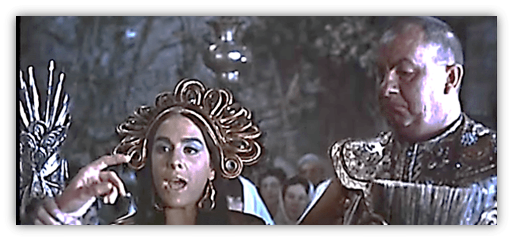 "Scene from a classic film featuring a woman with an ornate headdress speaking to a man in armor."