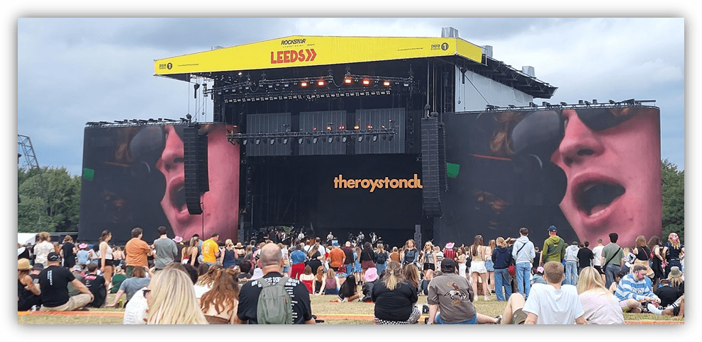 Crowd enjoying a live performance at Leeds Festival with large stage and screens.