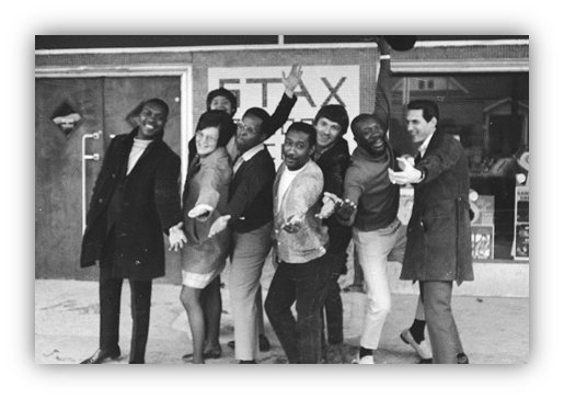Group of diverse individuals posing joyfully outside a storefront.