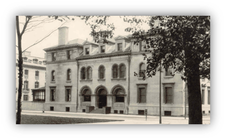 Historic building exterior with arched windows and a tree in the foreground.