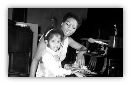Mother and daughter playing piano together in a black and white photo.