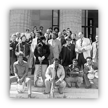 "Historic black and white photo of a diverse group of musicians posing together outdoors."
