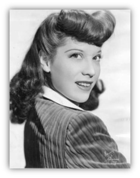 Vintage black and white portrait of a smiling woman with wavy hair and a striped jacket.