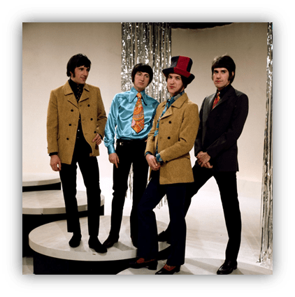 1960s music group posing in colorful outfits on stage with silver backdrop.