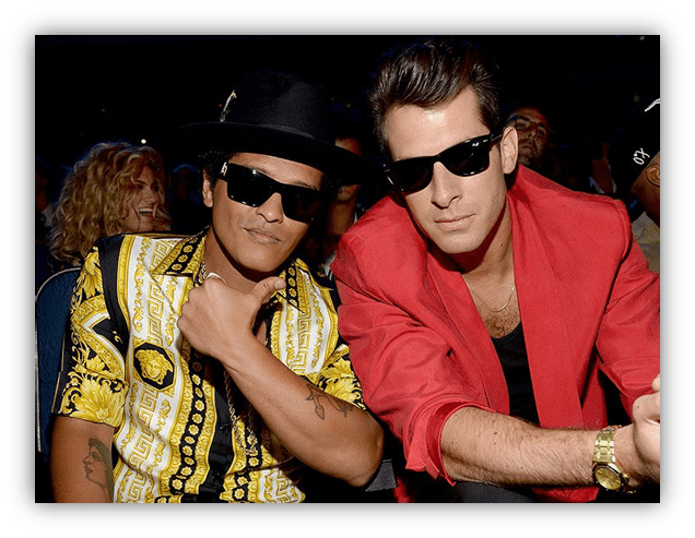 Bruno Mars and Mark Ronson posing together at an event, both wearing sunglasses and stylish outfits.