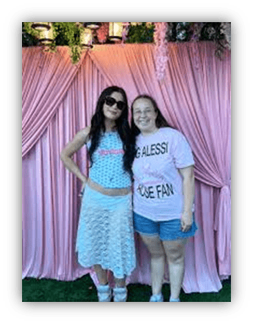 "Two women posing together at a pink-themed event backdrop."