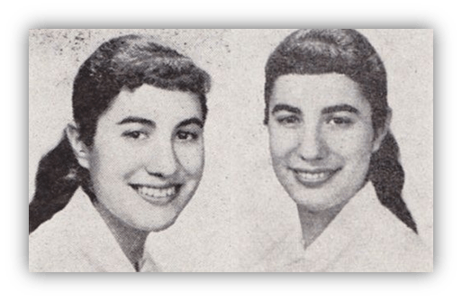 "Black and white photo of two smiling women with dark hair styled in ponytails."