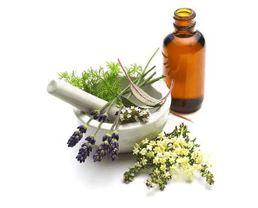 "Herbs and essential oils in a mortar and pestle with a brown glass bottle."