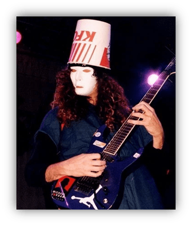 "Musician in a KFC bucket hat and mask playing electric guitar on stage."
