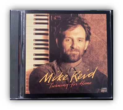 Album cover of Mike Reid's "Turning for Home" featuring the artist with a keyboard backdrop.