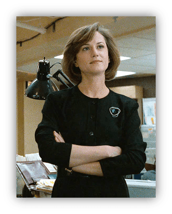 Woman in a black dress stands confidently in an office setting.