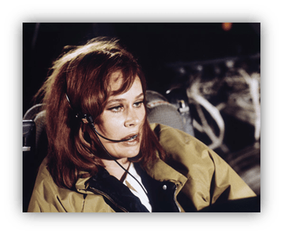 Actress wearing a headset in a cockpit scene from a classic film.