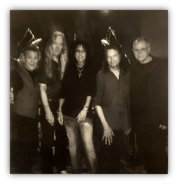 Black and white photo of five musicians posing together, featuring iconic rock artists.