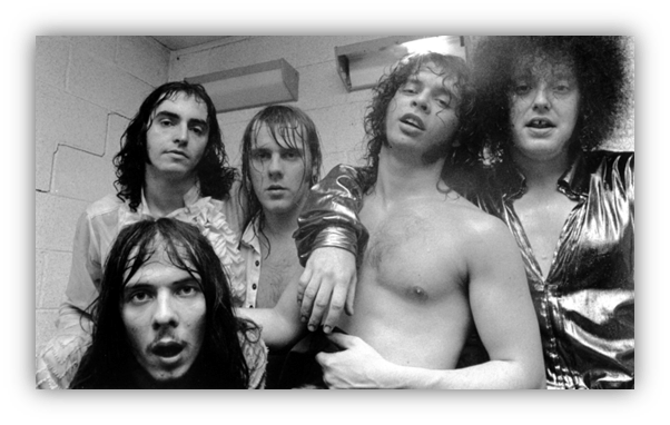 "Black and white photo of five musicians posing together in a backstage setting."