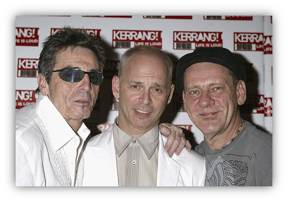 "Three men posing together at a Kerrang! event, showcasing their unique styles."