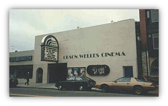 "Exterior of the Cesare Welles Cinema with marquee, vintage cars parked outside."
