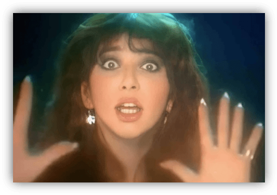 "Surprised woman with long hair, hands raised, and expressive eyes against a dark background."