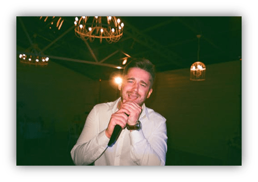 "Man singing into a microphone at a festive event."