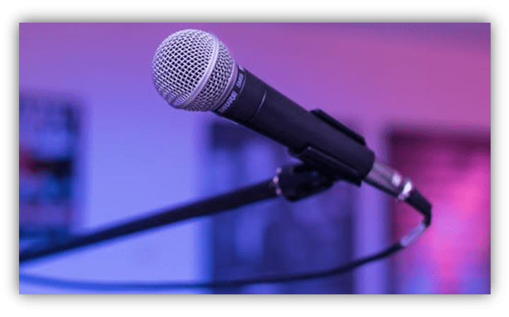 Microphone on a stand with a blurred colorful background.
