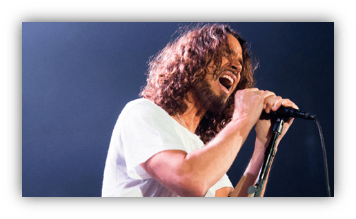 "Male singer passionately performing on stage with a microphone."