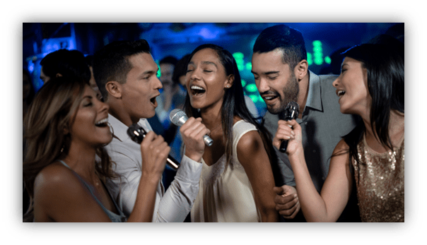 Group of friends singing together joyfully at a karaoke party.