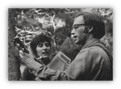 "Black and white photo of two musicians performing outdoors, one playing guitar and the other using a washboard."